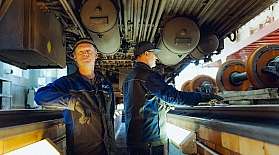 Zwei Mitarbeiter der RDC Deutschland Gruppe stehen in der Werkstattgrube unter einem Reisezugwagen.