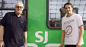 Carsten Carstensen und Oliver Noack vom Eishockey Club FASS Berlin stehen vor einem Wagen aus dem SJ EuroNight Nachtzug.