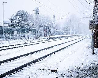Zugeschneite Bahnschienen an einem Bahnhof in Schleswig-Holstein.