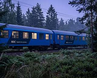 The RDC EuroNight travels through a forest at dusk.