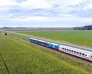 Auf der Bahnstrecke Niebüll nach Dagebüll ist ein NEG-Zug mit Kurswagen unterwegs.
