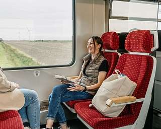 Zwei Frauen sitzen im Zug und genießen die Aussicht.